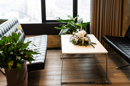 Making simple stylish christmas wreath with cedar branches, holiday workshop advent. Rustic christmas wreath with candles, pine cones, thread and ornaments on white wooden tableの写真素材