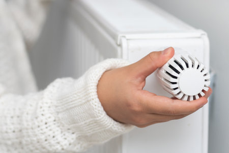 Girl warm ones hands near radiator at home.の写真素材