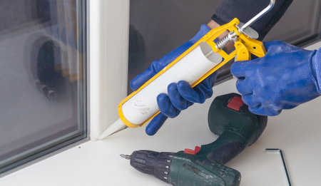 Construction worker sealing window with caulk indoorsの写真素材