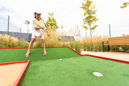 Beautiful little girl playing mini Golfの写真素材