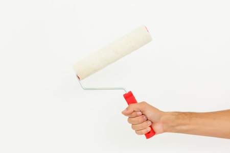 Woman hand holding a paint roller isolated on a white backgroundの写真素材