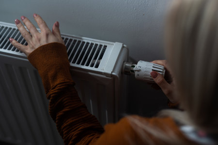 Heating season, woman warms her hands with heaterの写真素材