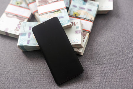 bundles of hryvnias and a smartphone. Online shopping and business with portable devicesの写真素材