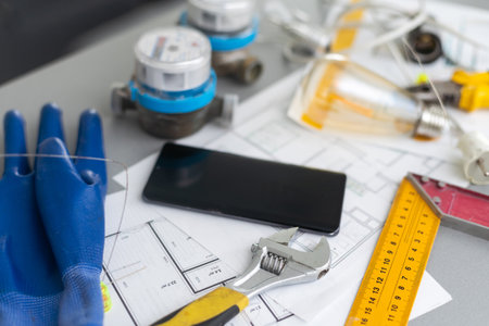 Blueprint flat project plan and office supplies on decorator table workspace. Swatches, tools, smartphone device and equipment background with copy space. Creative flat lay overhead top view concept.の写真素材