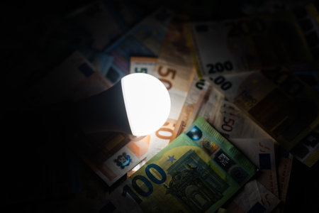 LED bulb on, with fluorescent bulb and incandescent bulb, with bills and coins next to it. Energy costs and evolution of light bulbsの写真素材