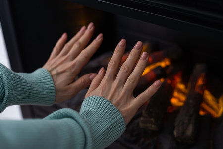 hand in front of an electric heater, inside an apartment in winterの写真素材
