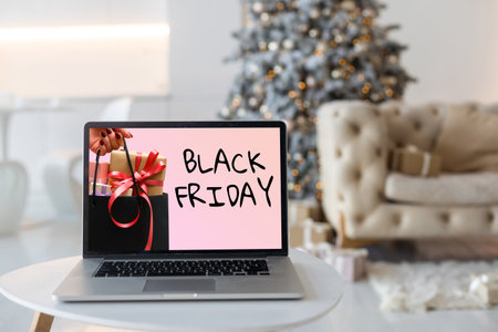 Black Friday shopping concept written in laptops black screen against blurred christmas lights backgroundの写真素材
