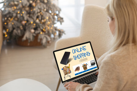 Christmas online shopping, sales and discounts promotions during the Christmas holidays, online shopping at home and lockdown coronavirus. Gifts on the laptop with blurred bokeh lightsの写真素材