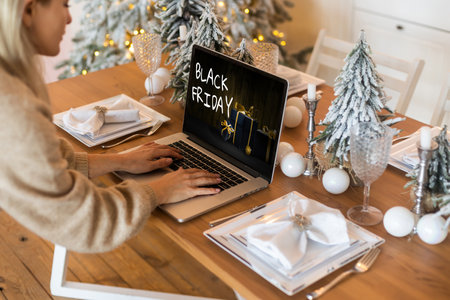 Black Friday shopping concept written in laptops black screen against blurred christmas lights backgroundの写真素材