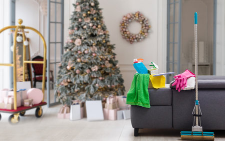 Cleaning before Christmas. Multicolored cleaning supplies. Sponges, rags and spray with festive decorations against backgroundの写真素材