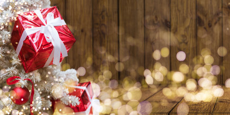 Red Christmas ball on a Christmas tree with a garland on the background of a wooden wallの写真素材