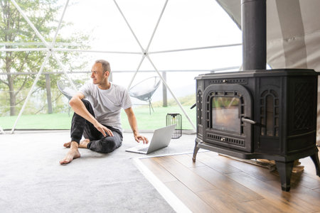 a man works on a laptop in a dome tent