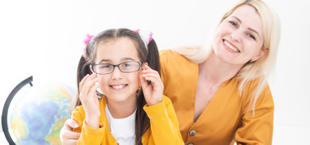 Private lesson. Attentive young woman tutor teacher help little girl pupil with studying math language correct mistakes explain learning material. Smiling mother assist small daughter with home taskの写真素材