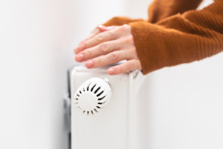 hand adjusting radiator temperature using thermostat. Home with central heating.の写真素材
