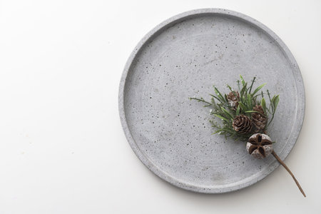 a pine branch on a cement round tray