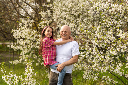 happy granddaughter hugging her smiling grandfather on green lawnの写真素材