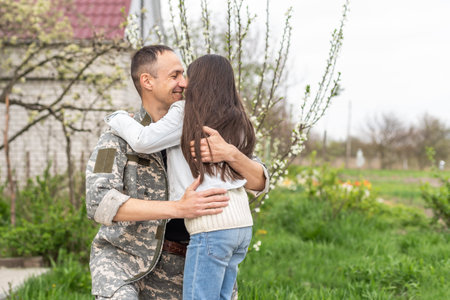 Little child is very happy her father came back from army. Little kid is hugging her fatherの写真素材