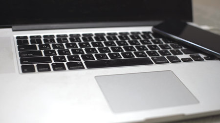 hand plugging the charger into cell phone against laptop computer
