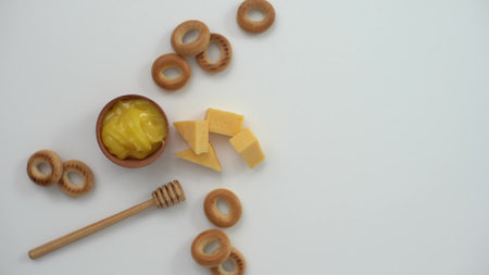 honey in a wooden bowl, bagels and cheese on a white backgroundの写真素材