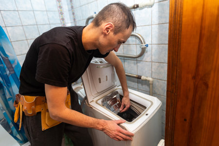 repair of household appliances at home with their own hands. the repairman repairs the washing machine. services for the repair of household appliances at home and in the workshopの写真素材