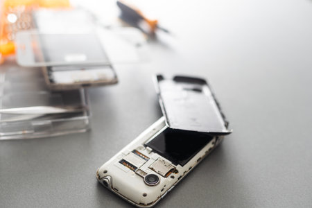 Technician repairing mobile phone at table, closeupの写真素材