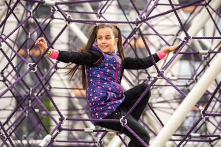 Cute teenage girl in the rope labyrinth kid park attractionの写真素材