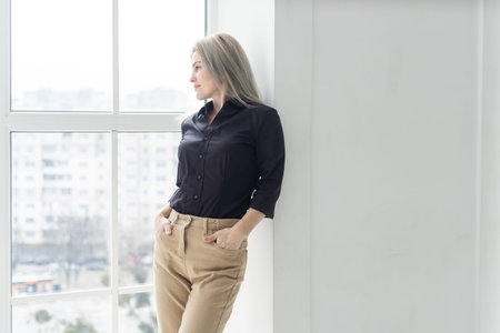 Young business woman wearing suite standing near window.