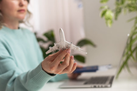 Positive happy woman going on summer holidays, sitting at office with toy plane and showing...