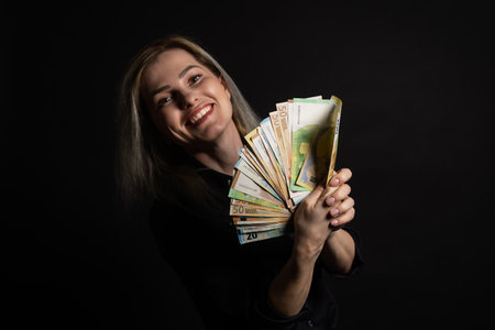 Happy business woman holding euro currency notes, isolated over a black backgroundの写真素材