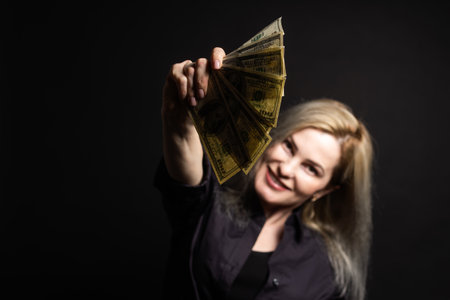 Successful beautiful business young woman holding money US dollar bills in hand, business conceptの写真素材