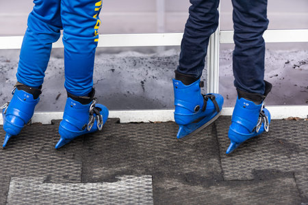 Close-up of family of three wearing skates standing on skating rink they going to skate.