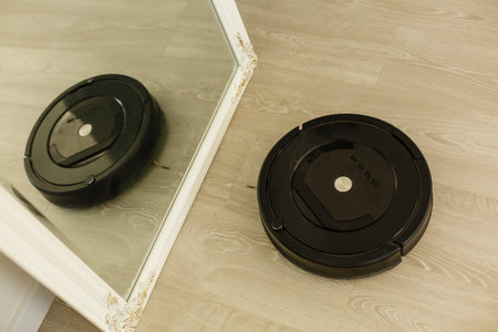 The robot vacuum cleaner drives on the laminate floor. Smart House. Home assistant concept.の写真素材