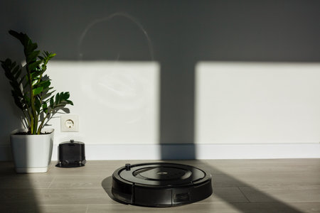 The robot vacuum cleaner drives on the laminate floor. Smart House. Home assistant concept.の写真素材