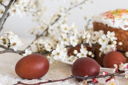 Easter composition. A blooming apricot branch, painted eggs and a glazed Easter cake decorated with...