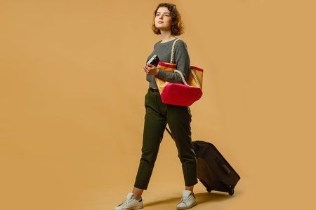 concept of travel. happy woman girl with suitcase and passport on yellow colored background.