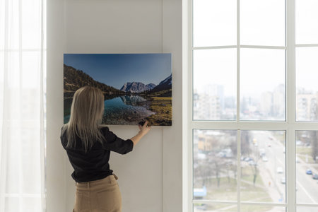 Girl hanging a photo canvas on a wall