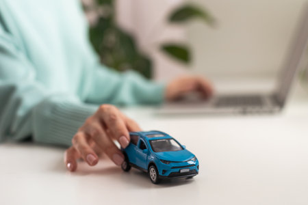 hands of a woman on a desk behind a keyboard with a small model car. Insurance concept. Credyn for the car.の写真素材