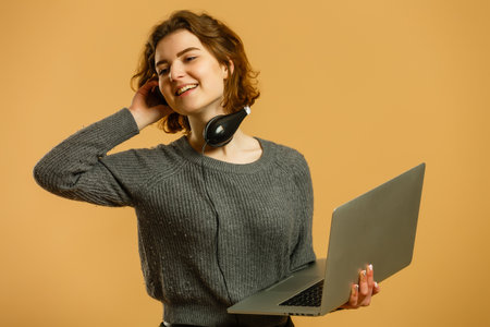 Modern happy millennial teenage girl with sunglasses, headphones smiling showing peace gesture over yellow background, vibrant colorsの写真素材