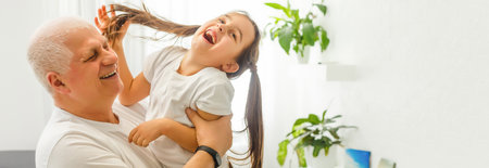 Middle-aged caucasian man playing with a little girl on the river bank. Man stands astoop ans holds his granddaughter on his back as she is "flying" Everybodys happyの写真素材