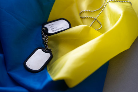 Army identification badges, ribbons of the Ukrainian flag, scattered machine-gun cartridges and live ammunition on a white background. Concept: war in Ukraine, military special operation, conscriptionの写真素材