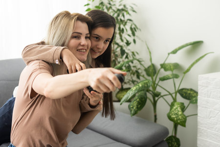 Photo of domestic funny blond lady mom daughter sitting comfy couch hold joystick playing video games stay home safety quarantine spend weekend together best friends living room indoors.の写真素材