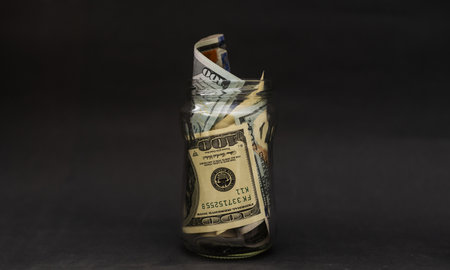 Many 100 US dollars bank notes in a glass jar isolatedの写真素材