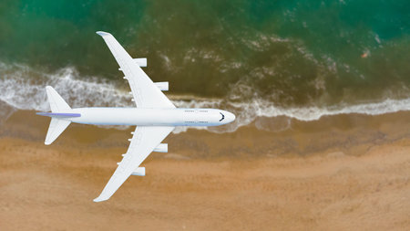 Airplane flying over beach with palm tree, white sand and turquoise oceanの写真素材