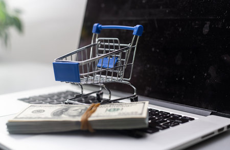 toy shopping cart with dollar banknotes on white,