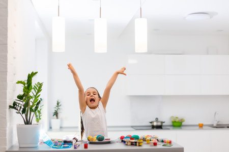 Little girl painting Easter eggs in the kitchenの写真素材