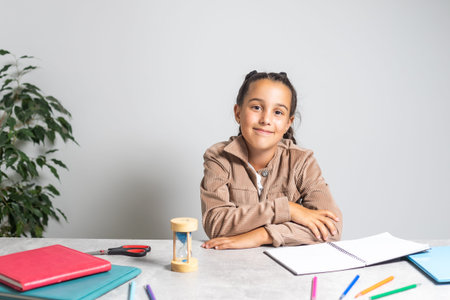 Smart small Caucasian girl child sit at table at home write in exercise book prepare homework for...