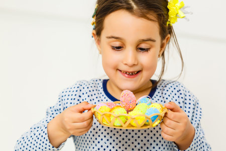 Cute little child on Easter day. Girl holding basket with painted eggs