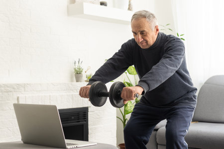 Online workout. elderly man doing exercise with online tutorial at home, panorama, free spaceの写真素材