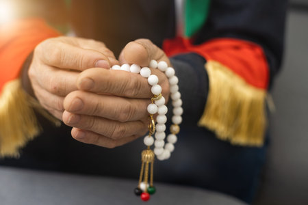 an elderly man prays with a rosary and the flag of the United Arab Emiratesの写真素材