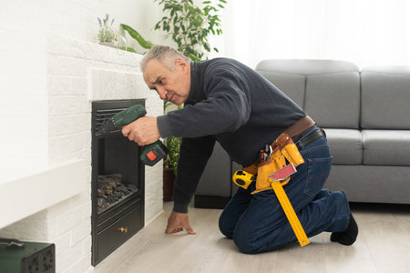 an elderly man repairs a fireplaceの写真素材
